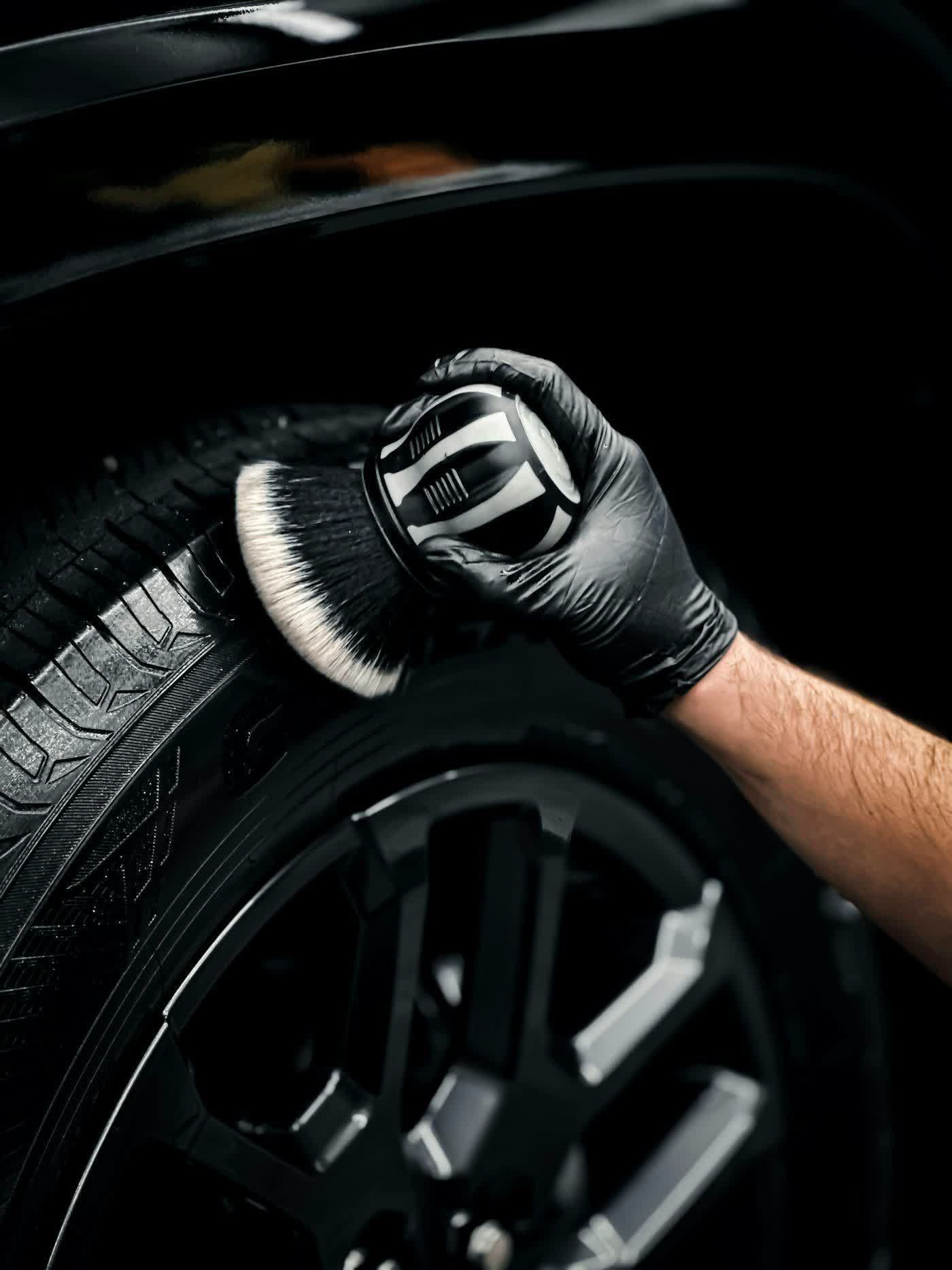 A gloved hand brushing the face of a wheel