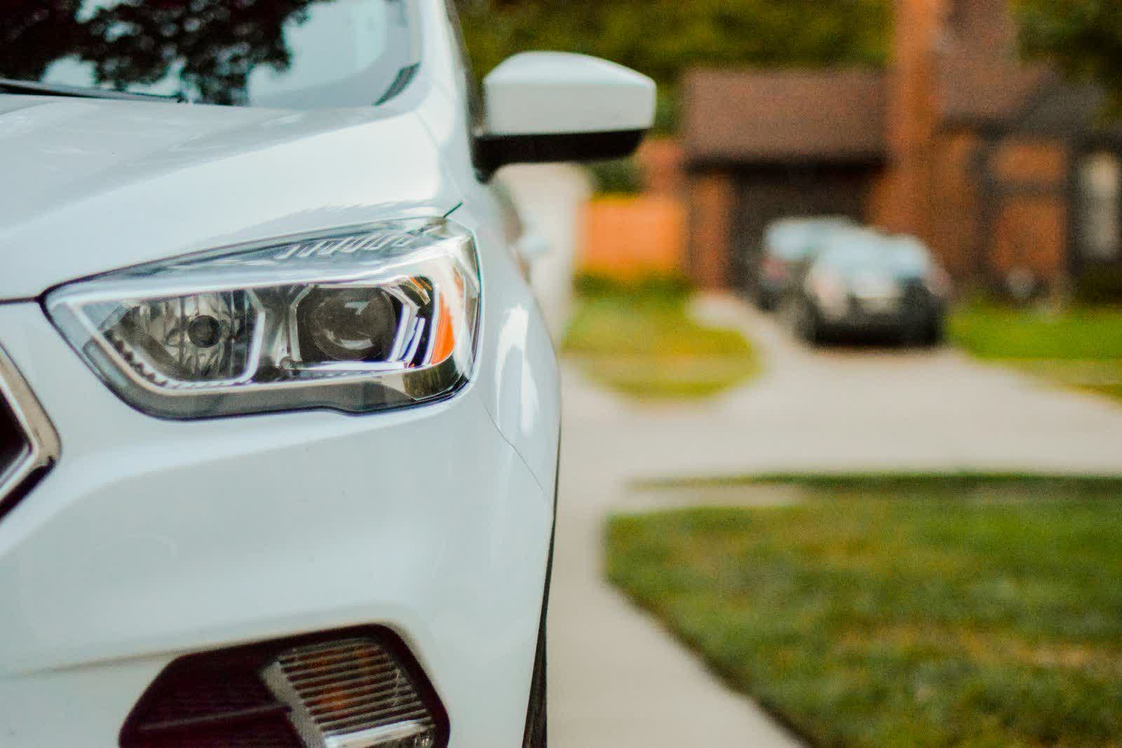 The front corner of a white SUV parked on a residential driveway