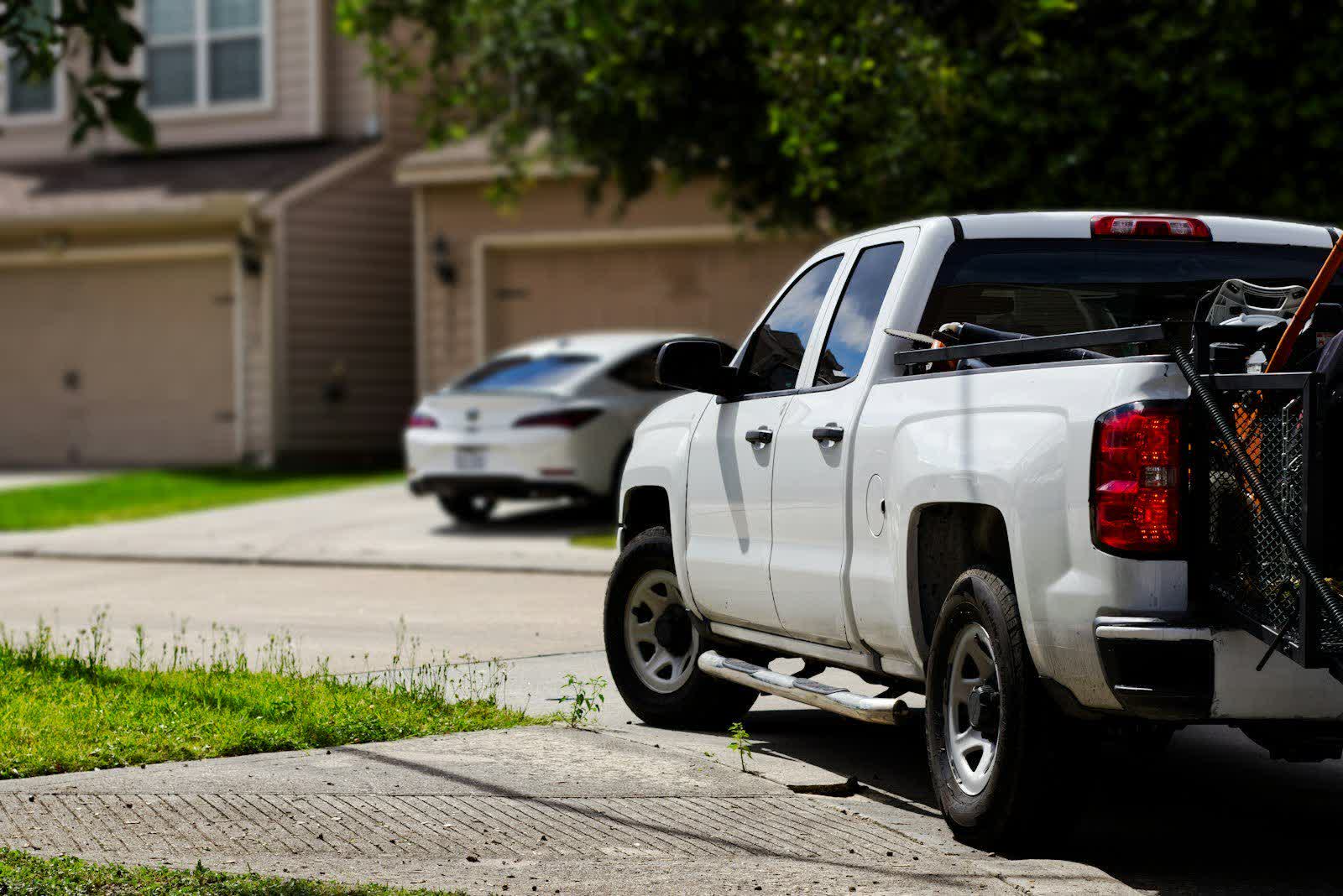 A pickup and a sedan left out on driveways in front of newly built houses