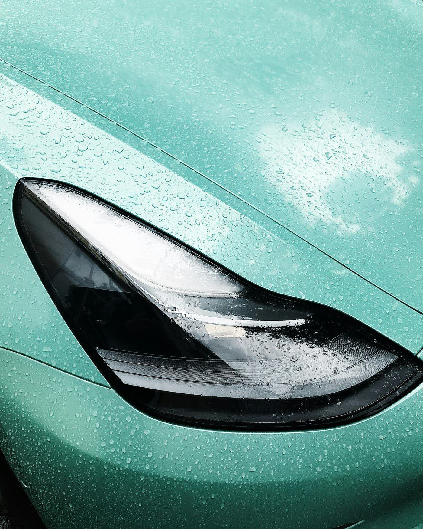 Water beading across the front corner and headlight of a green coated car