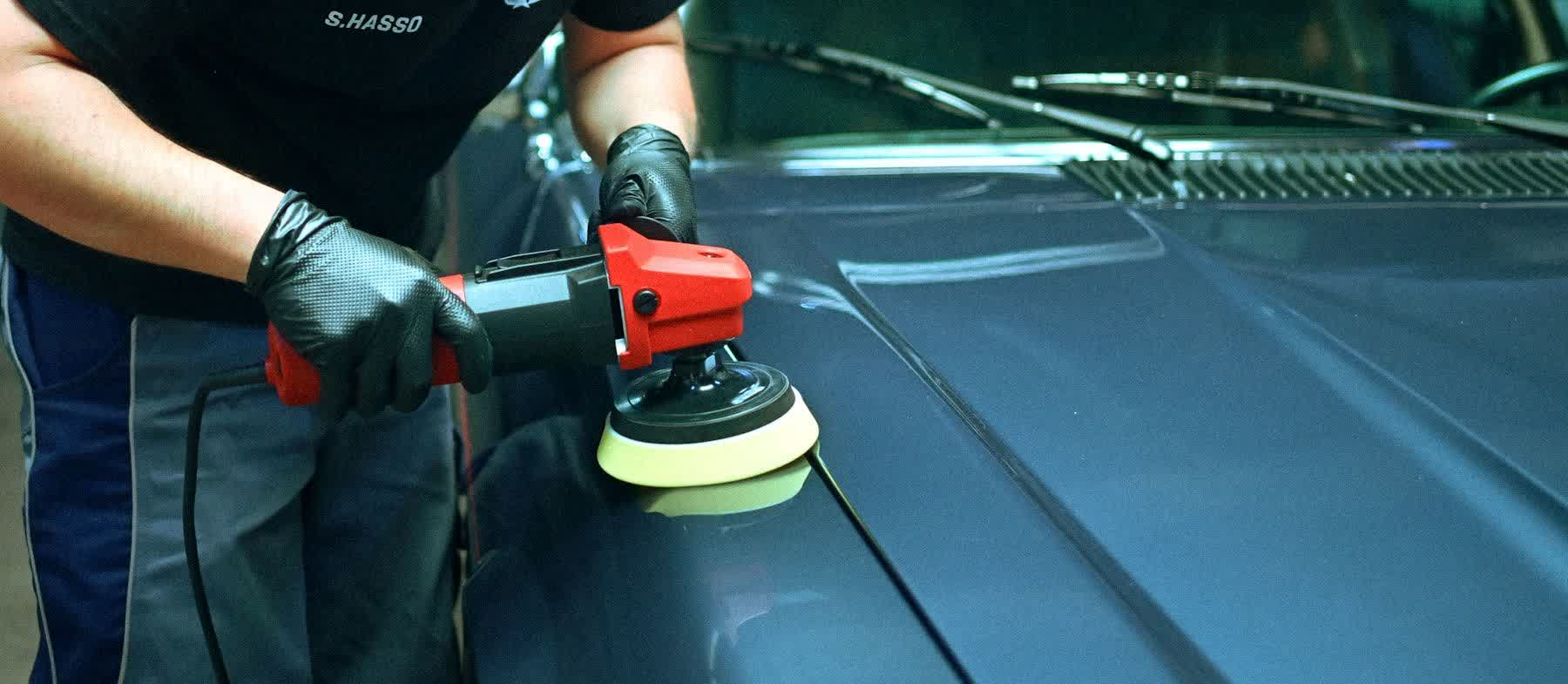 A polisher loaded with a fresh pad worked across a teal panel